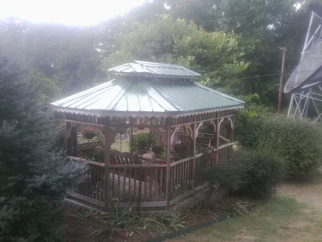 Green metal roof on a backyard gazebo surrounded by garden beds in Nashville